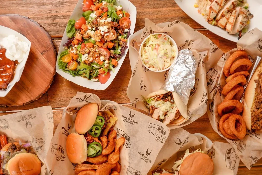 Overhead view of branded casual dining and barbecue food on rustic table.