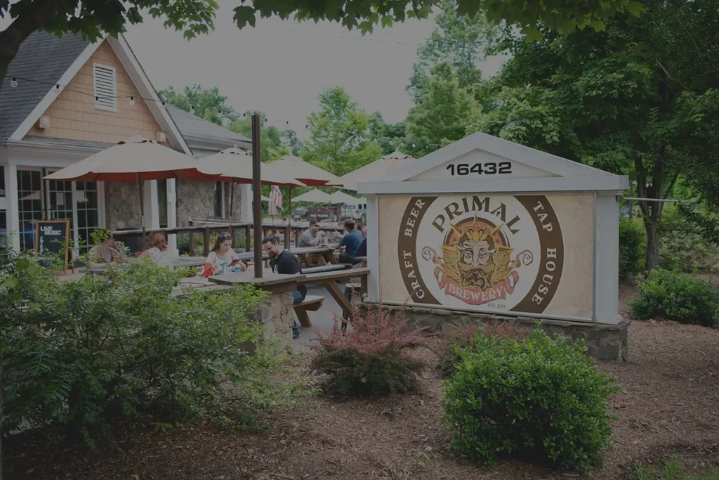 Primal Brewery Tap House exterior, patio with people and umbrellas.