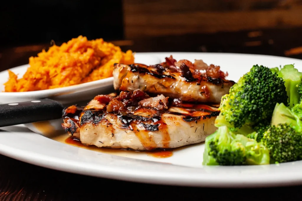 Two grilled chops with glaze, broccoli, and mashed orange vegetables.