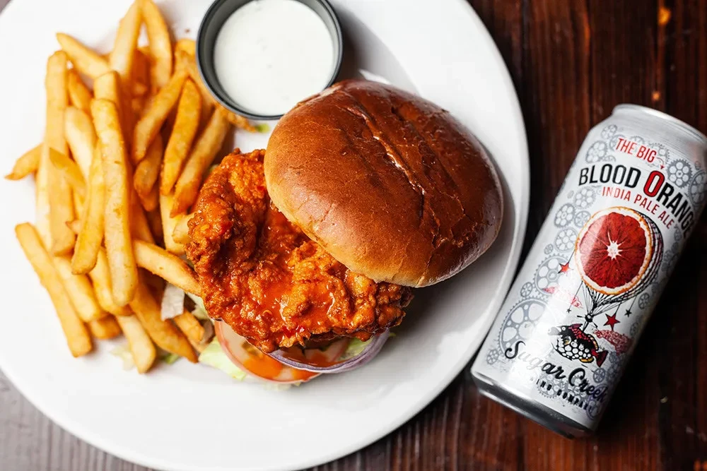 Spicy fried chicken sandwich meal with fries and blood orange IPA.