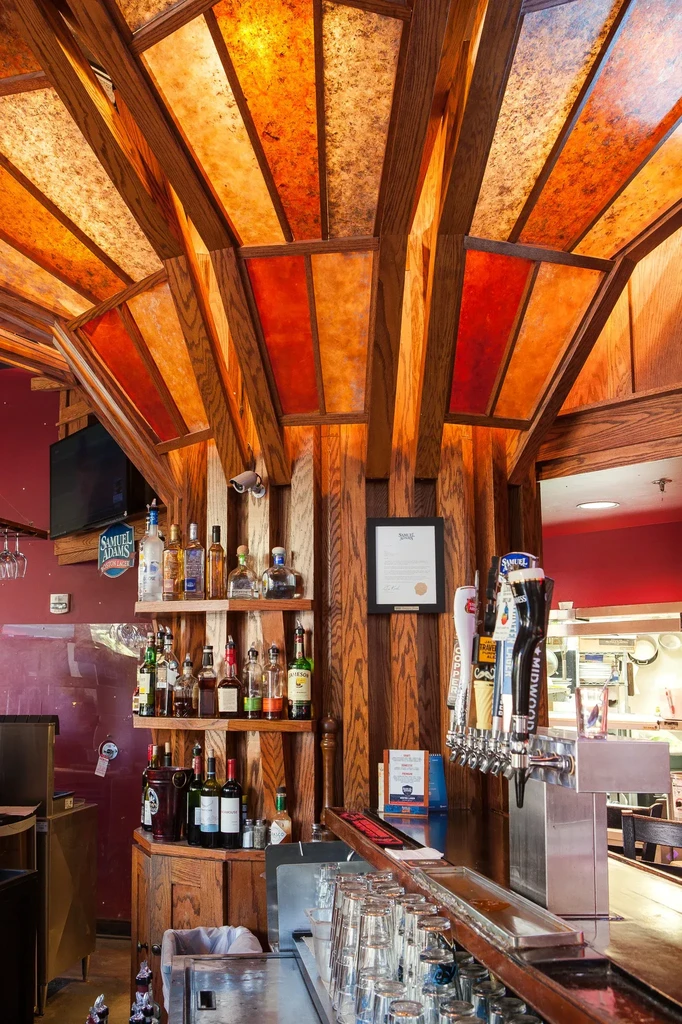 Well-stocked bar with beer taps and illuminated amber-red ceiling.