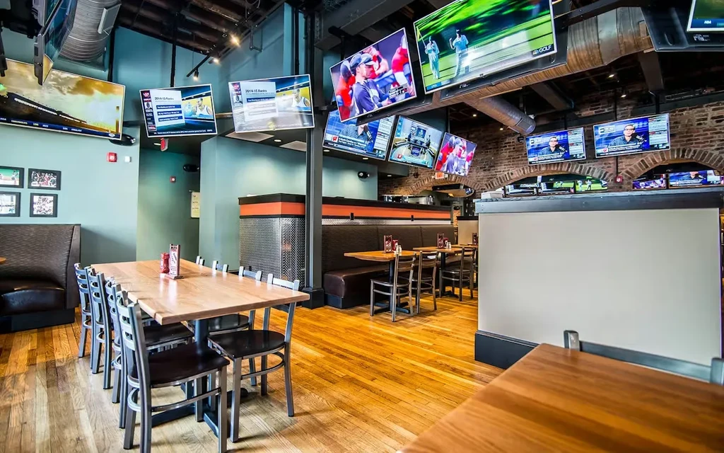 Restaurant and sports bar interior with communal tables and many sports TVs.