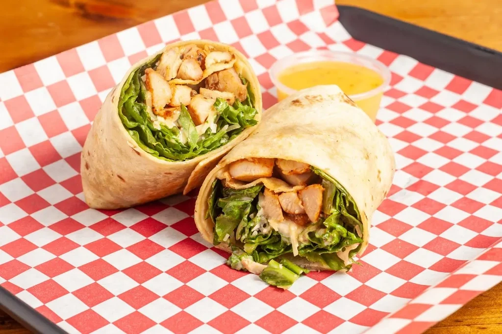 Grilled chicken wrap halves with lettuce and creamy sauce.