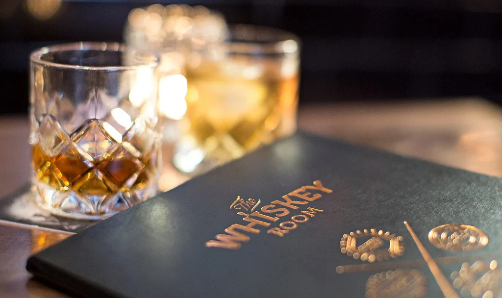 Gold-embossed 'The WHISKEY ROOM' menu with two whiskey glasses.