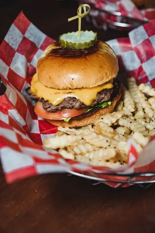 Cheeseburger with melted cheese, pickle, lettuce, and seasoned waffle fries.
