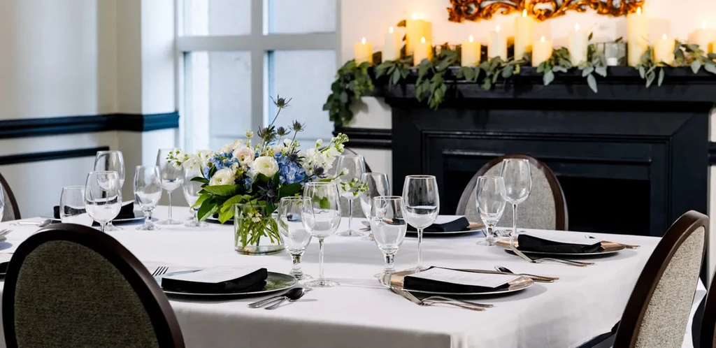Elegantly set formal dining table with a floral centerpiece and multiple place settings.