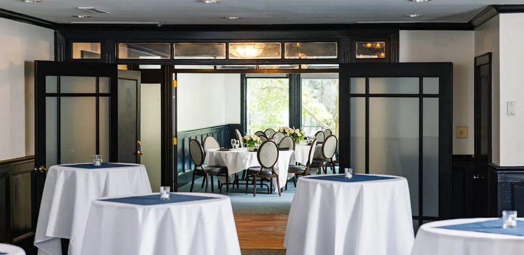 Elegant restaurant interior with cocktail tables and bright dining area beyond.