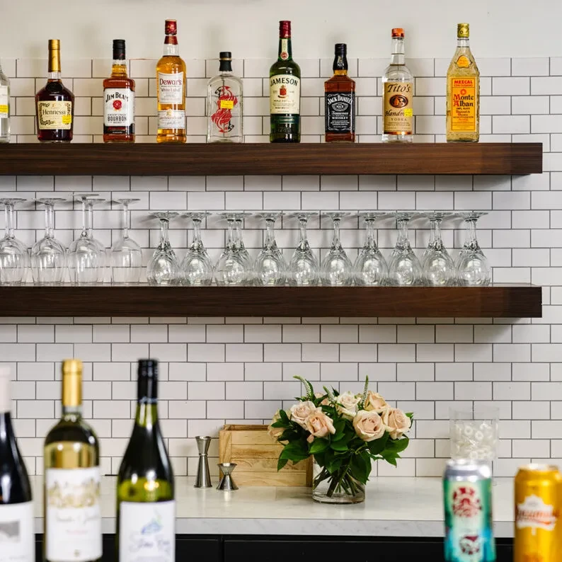 Restaurant bar showing liquor bottles, hanging wine glasses, and pink roses.