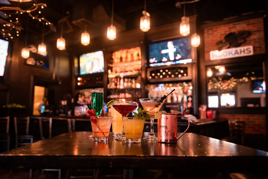 Six diverse cocktails on a reflective table in a vibrant bar interior.