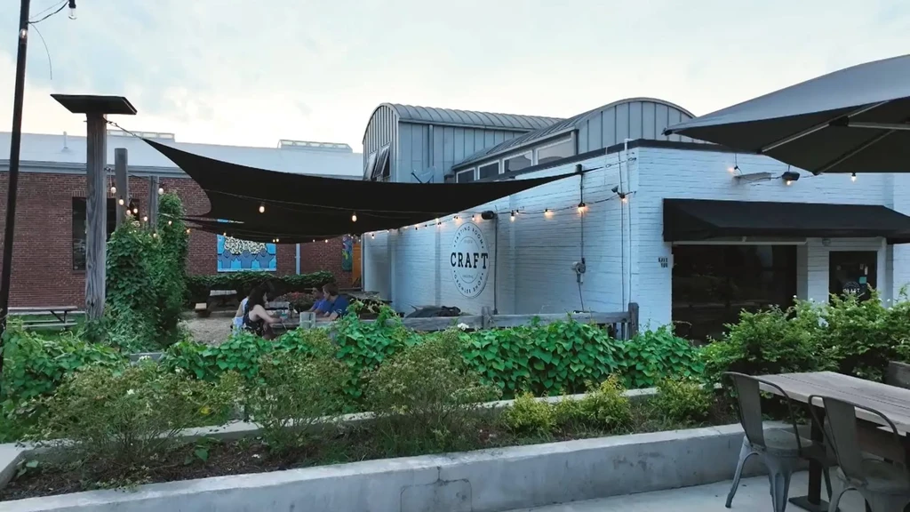 Outdoor patio of a CRAFT Tasting Room with string lights and plants.