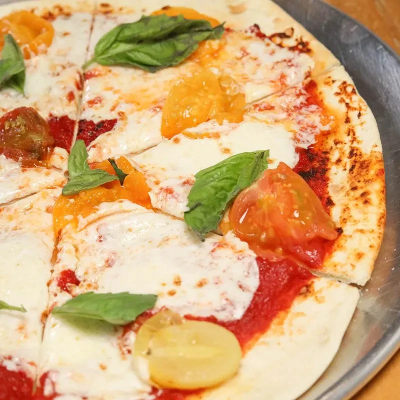Freshly baked pizza with mozzarella, basil, and colorful sliced tomatoes.