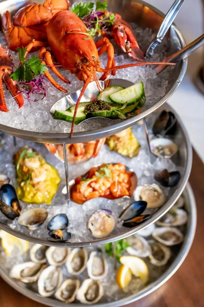 Three-tiered seafood tower with lobster, caviar, shellfish, oysters, and ice.