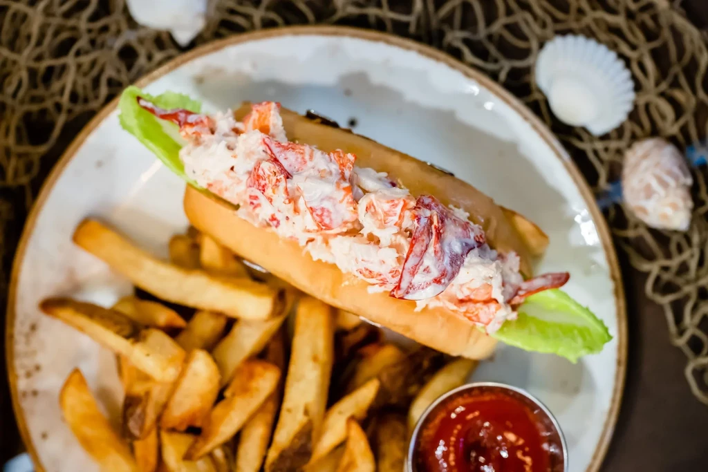 Generously filled lobster roll, golden fries, and ketchup.