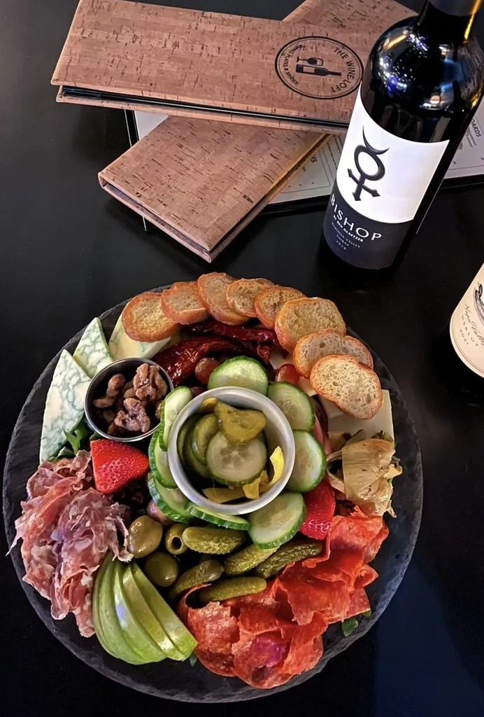 Artfully arranged charcuterie board with meats, cheeses, fruits, and wine.