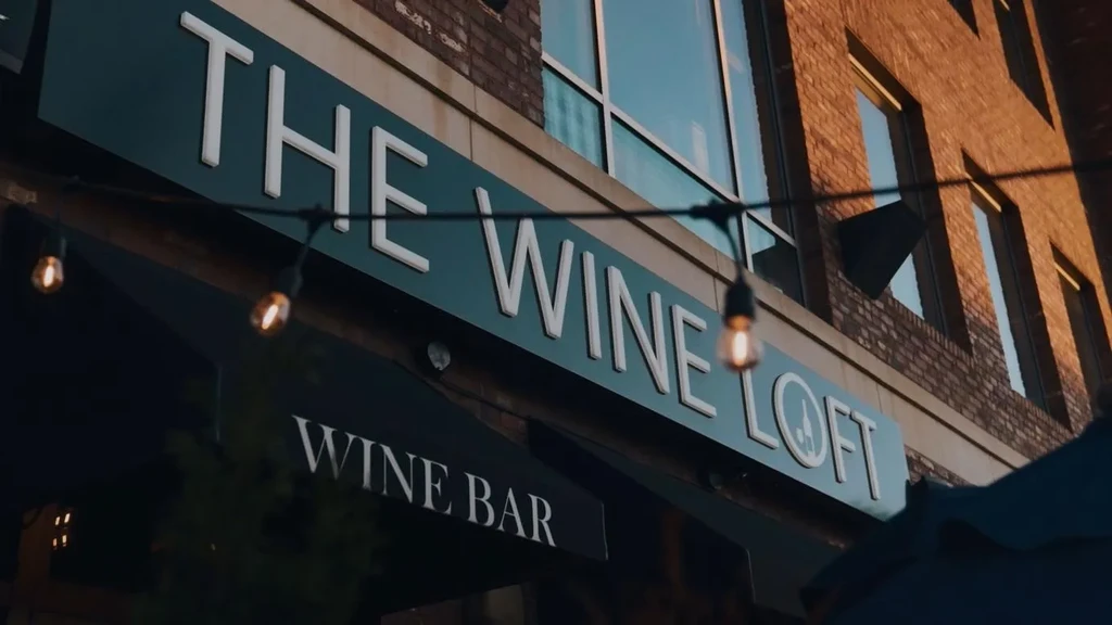 Dark teal 'The Wine Loft' sign in warm evening light.