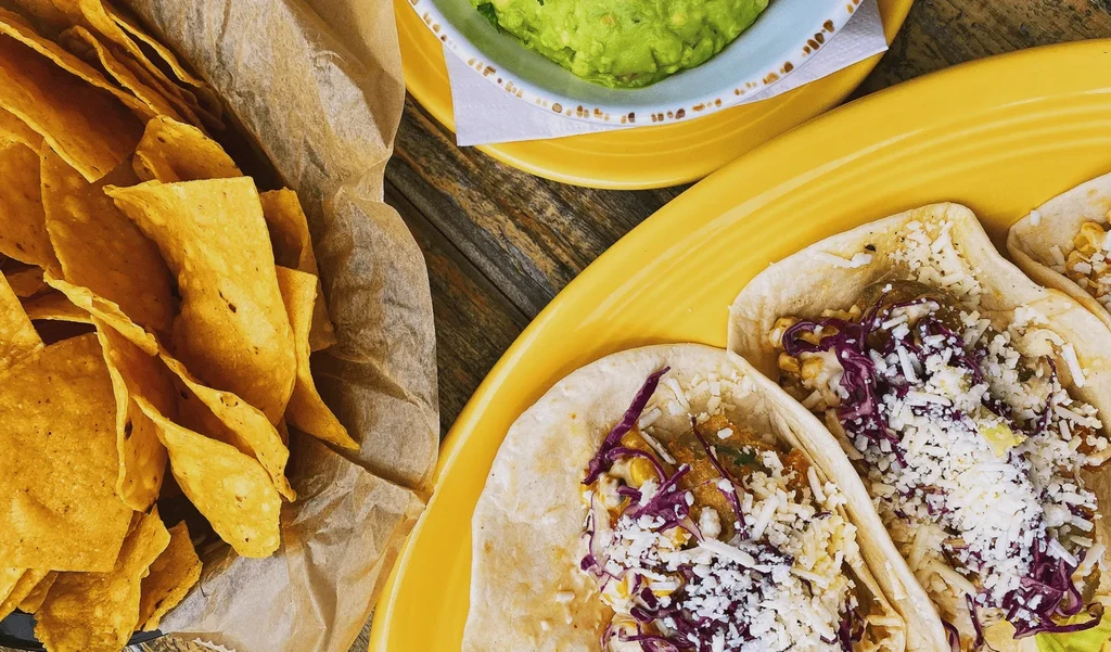 Vibrant Mexican tacos, tortilla chips, and guacamole on a rustic table.