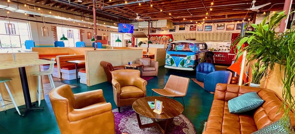 Eclectic restaurant interior with varied seating, vintage VW bus, surf decor.
