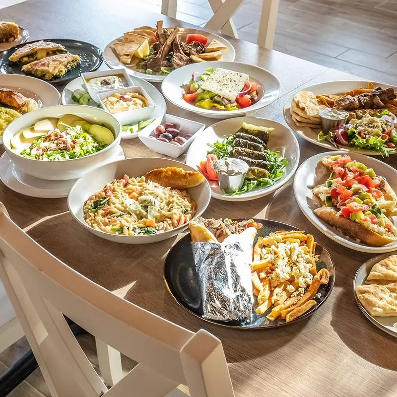 A large spread of Mediterranean and Greek dishes on a wooden table.