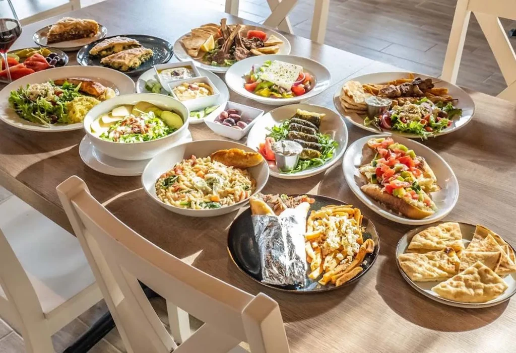 High-angle shot: abundant Greek-Mediterranean food on a large wooden table.