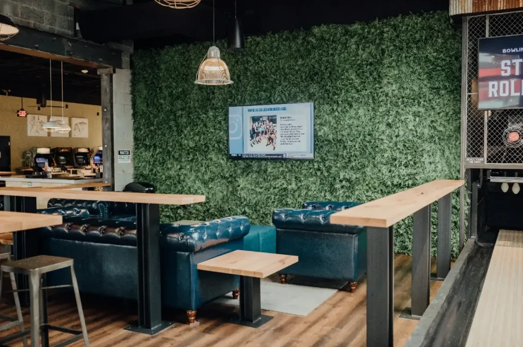 Interior of modern entertainment venue with blue booths, green wall, and bowling.