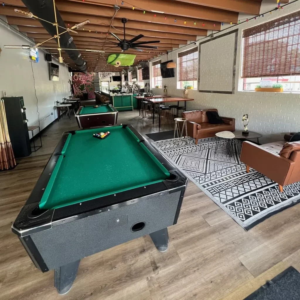 Spacious bar lounge with two green felt pool tables, no people.