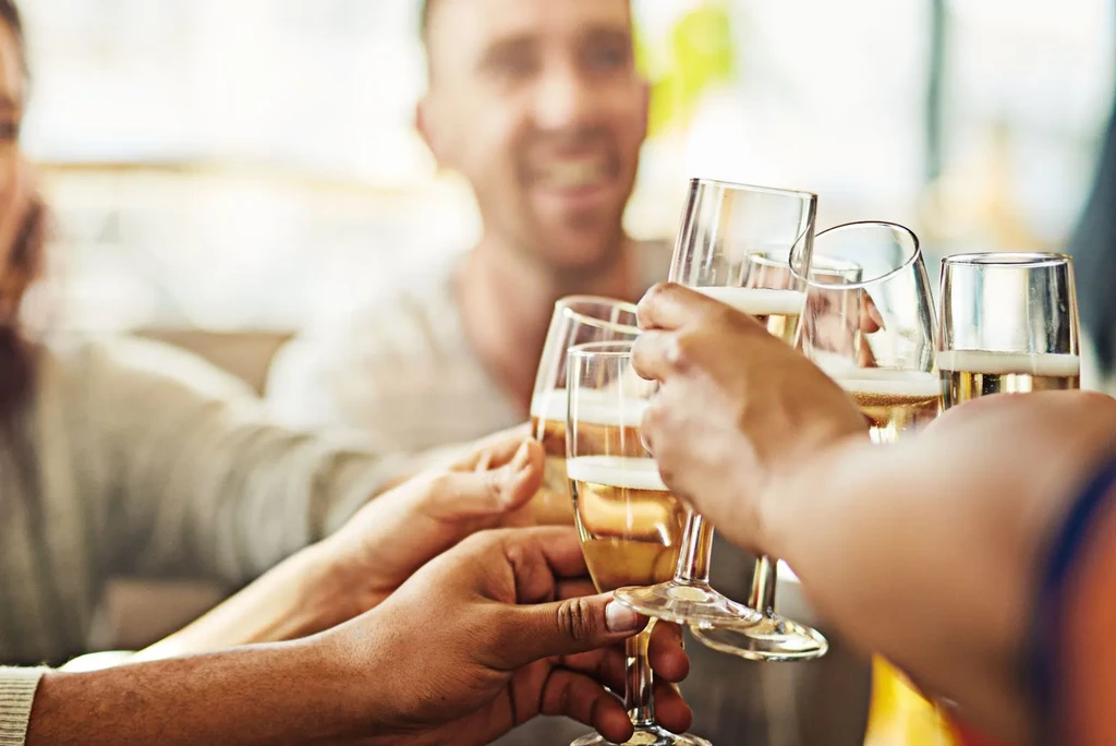 Close-up: Diverse hands hold glasses filled with golden, bubbly champagne.