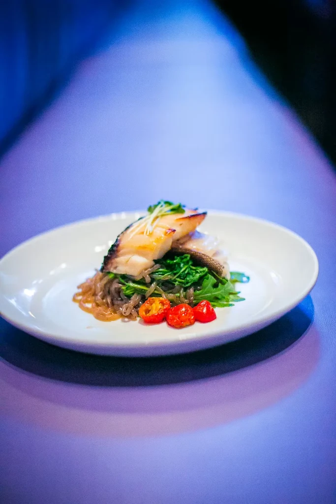 Pan-seared fish with crispy skin, arugula, and cherry tomatoes.