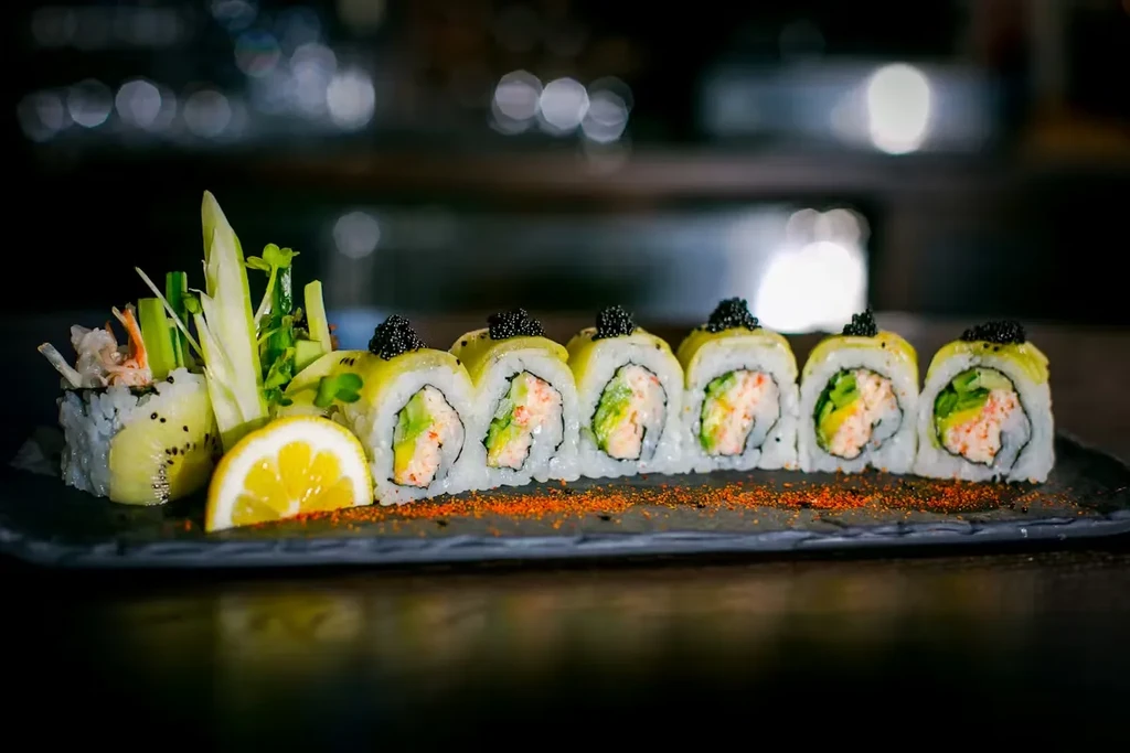 Close-up of assorted sushi rolls with caviar, shrimp, avocado, and lemon.