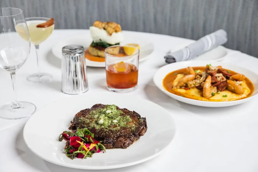 Professionally arranged restaurant table with gourmet steak, drinks, and dishes.