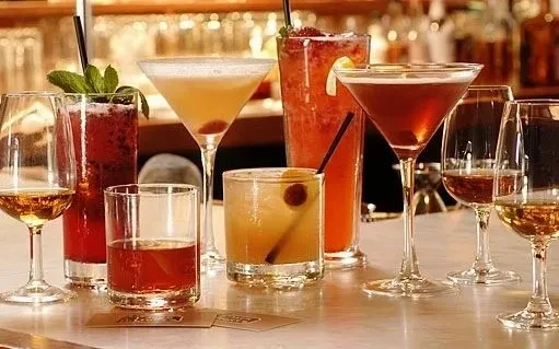 Eight varied cocktails with garnishes on a bar counter; "MIAMI" visible.
