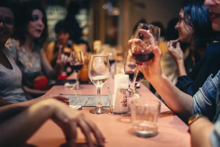 Group of people enjoying drinks at a restaurant table with blurred faces.