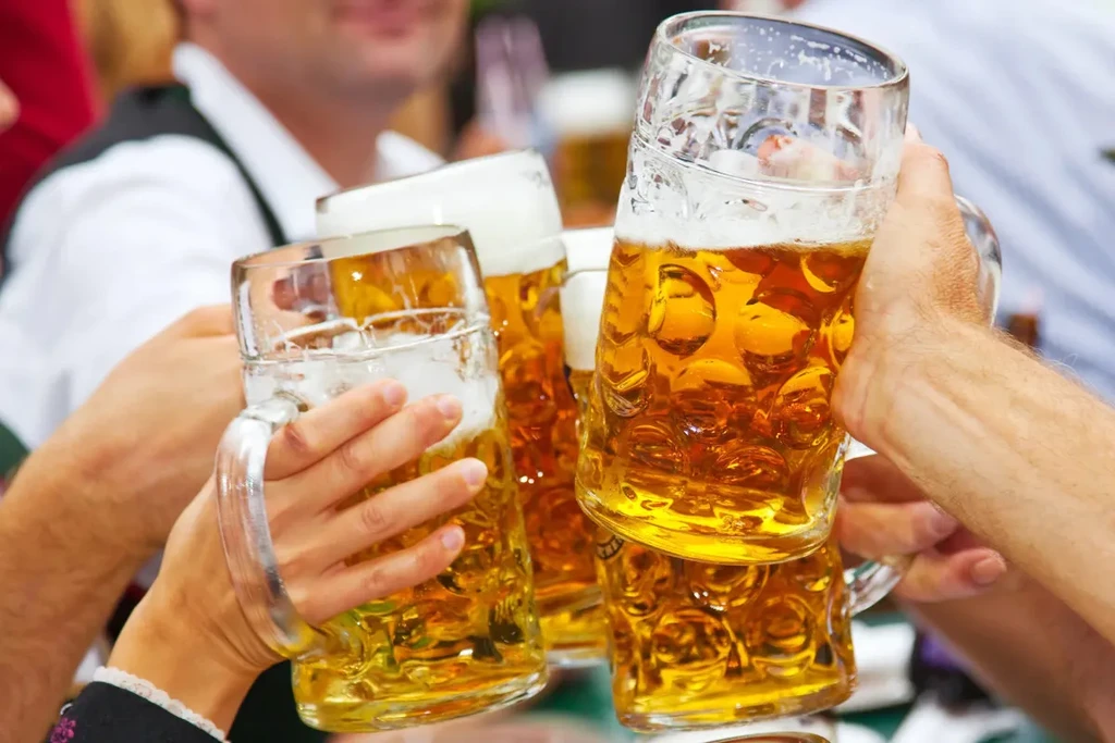 Four hands hold up large beer steins in a festive toast.