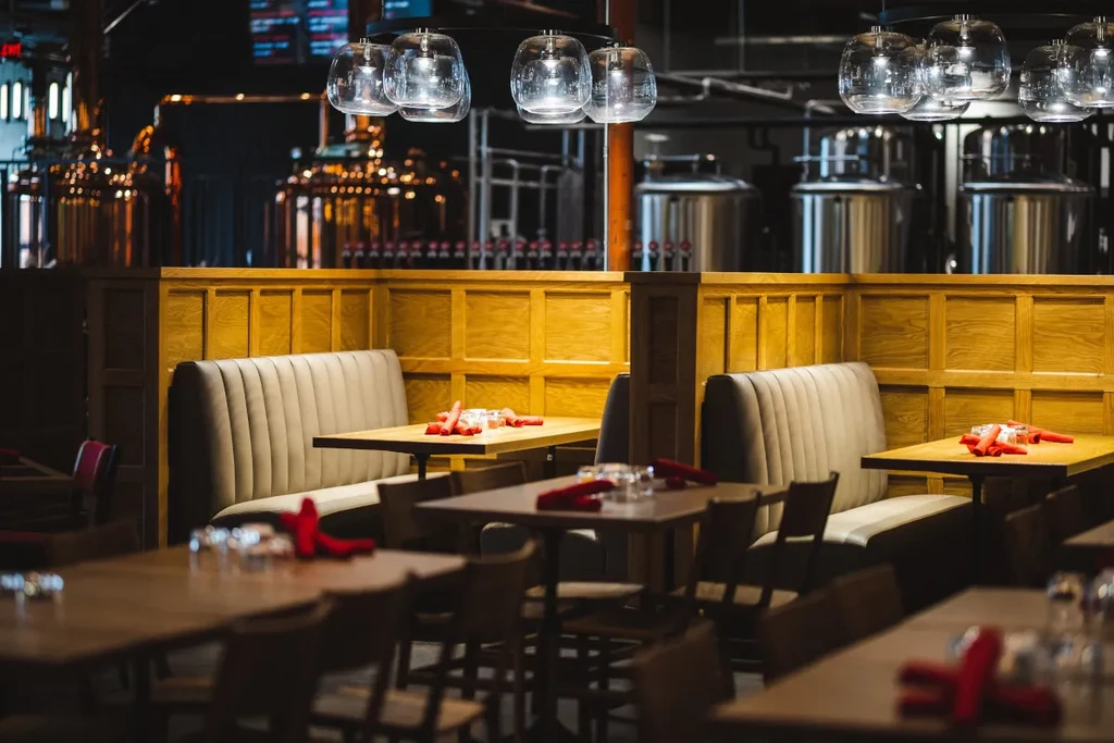 Brewpub dining area with booths and large brewing tanks.
