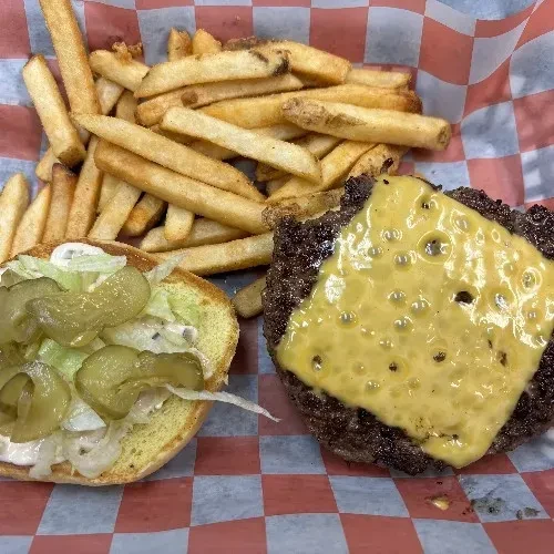 Unassembled cheeseburger with melted cheese, lettuce, pickles, and golden fries.