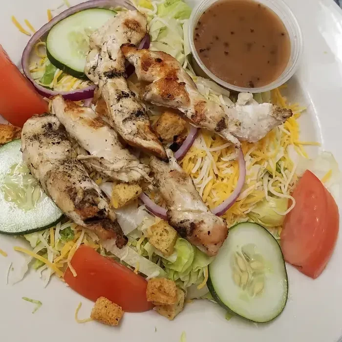 Grilled chicken salad with lettuce, cheese, tomatoes, cucumbers, croutons, dressing.