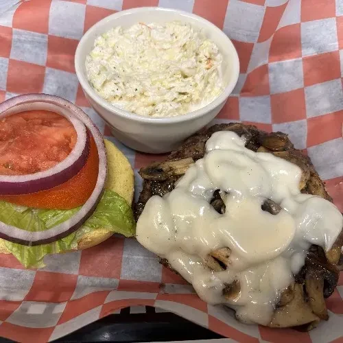 Top-down: Deconstructed burger, melted cheese, mushrooms, coleslaw, checkered paper.