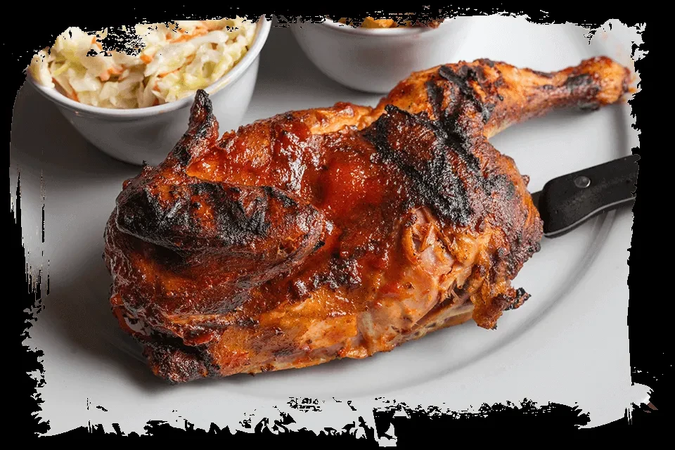 Roasted half-chicken on white plate with knife and coleslaw.