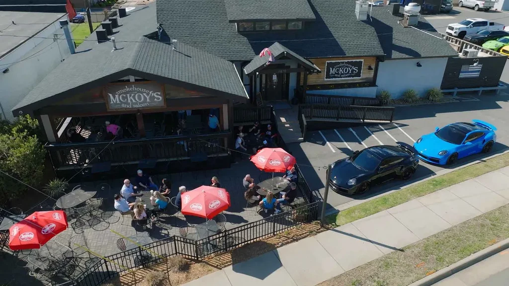 High-angle view of McKoy's Smokehouse with diners and two parked Porsches.