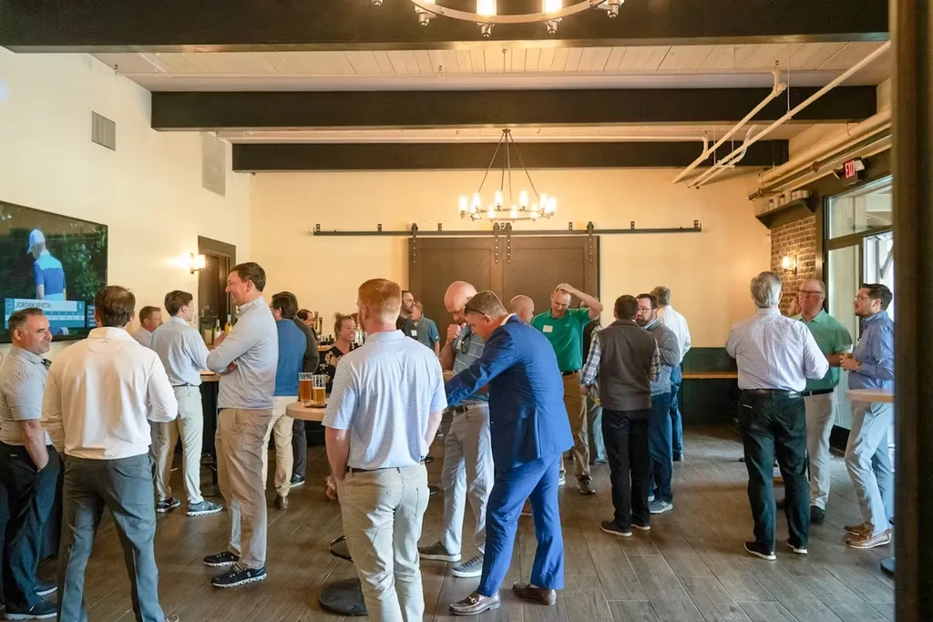 Group of men socializing in a modern bar with golf on TV.