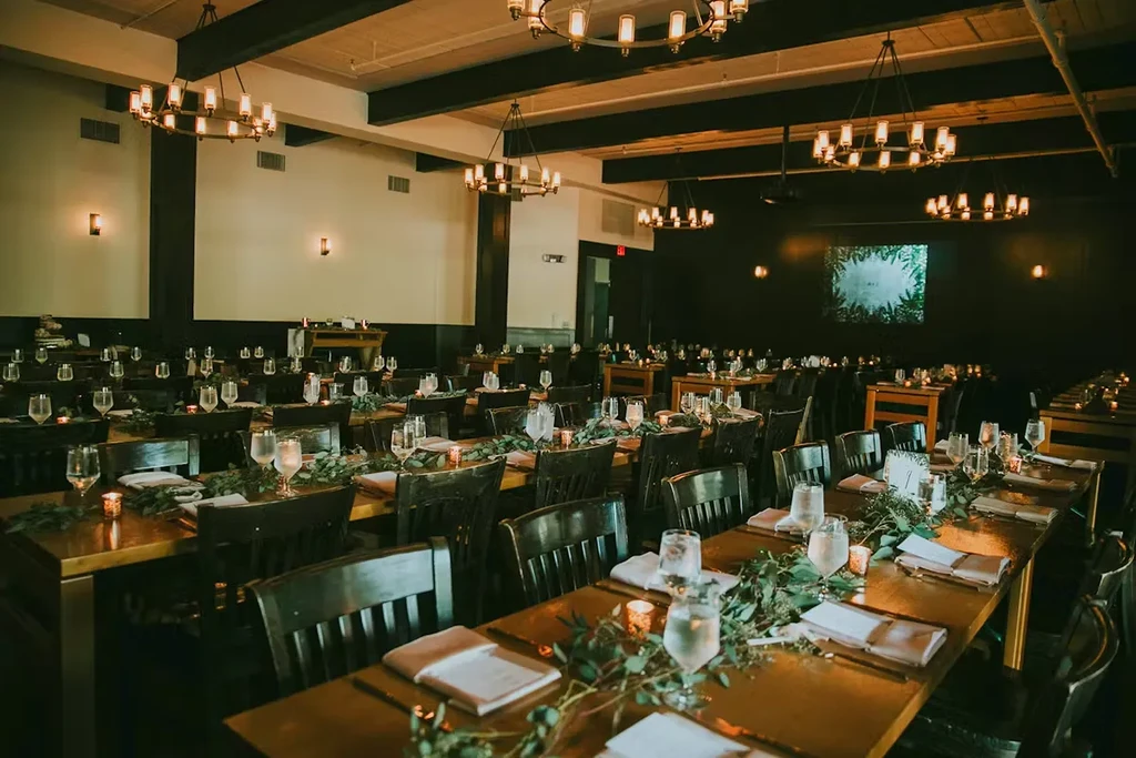 Large event hall with tables decorated with garlands and candles.