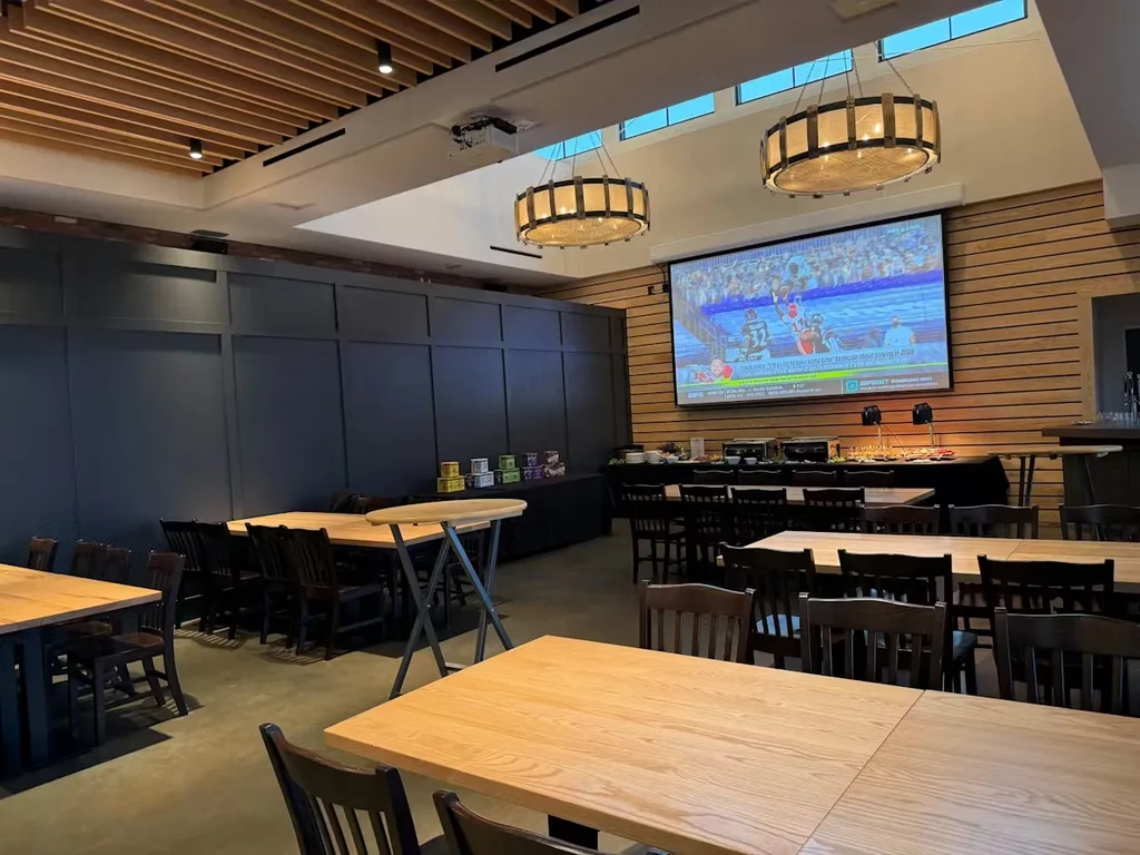 Modern restaurant interior featuring a buffet and large sports screen.