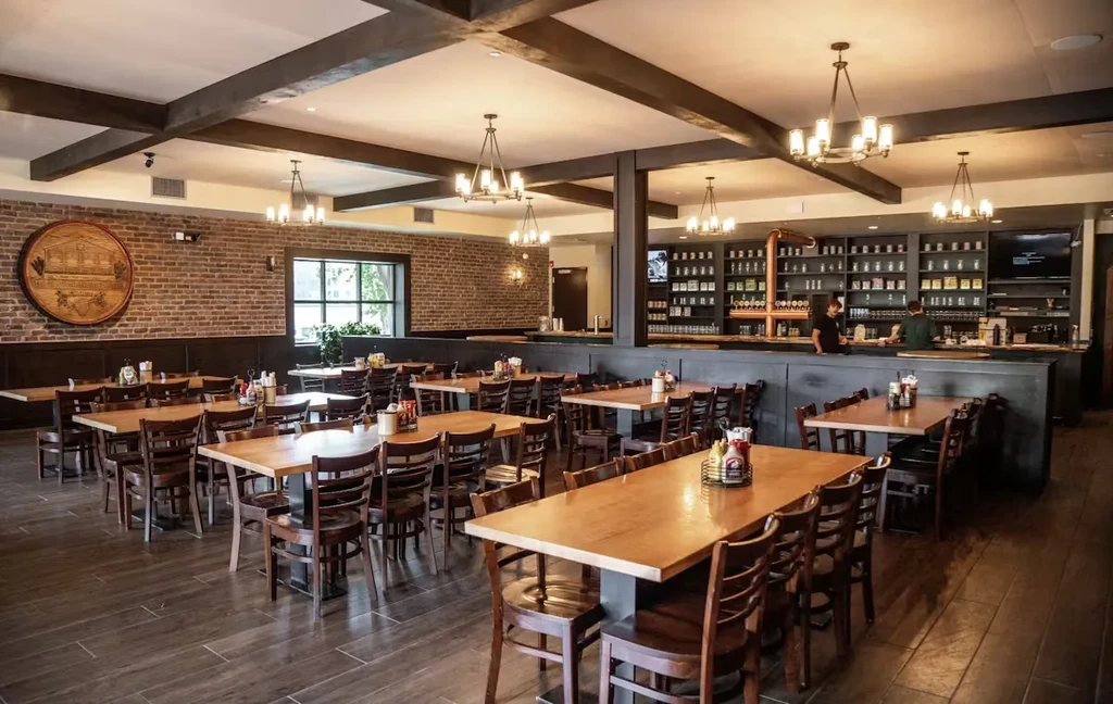 Wide view of a rustic restaurant's dining room and busy bar.