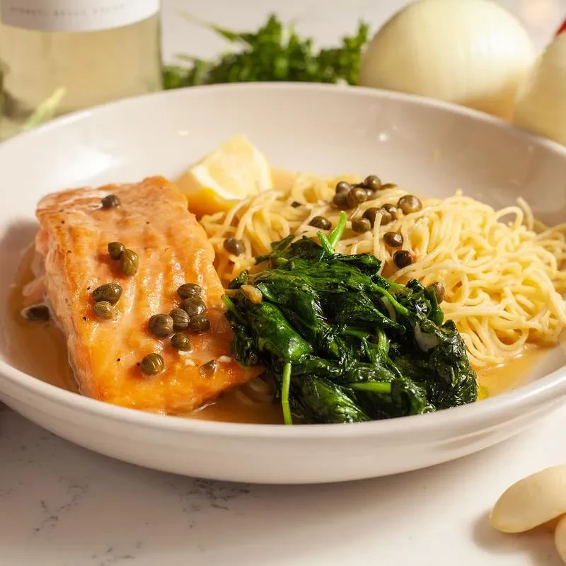 Salmon fillet with crispy skin, pasta, sautéed greens, capers, lemon.
