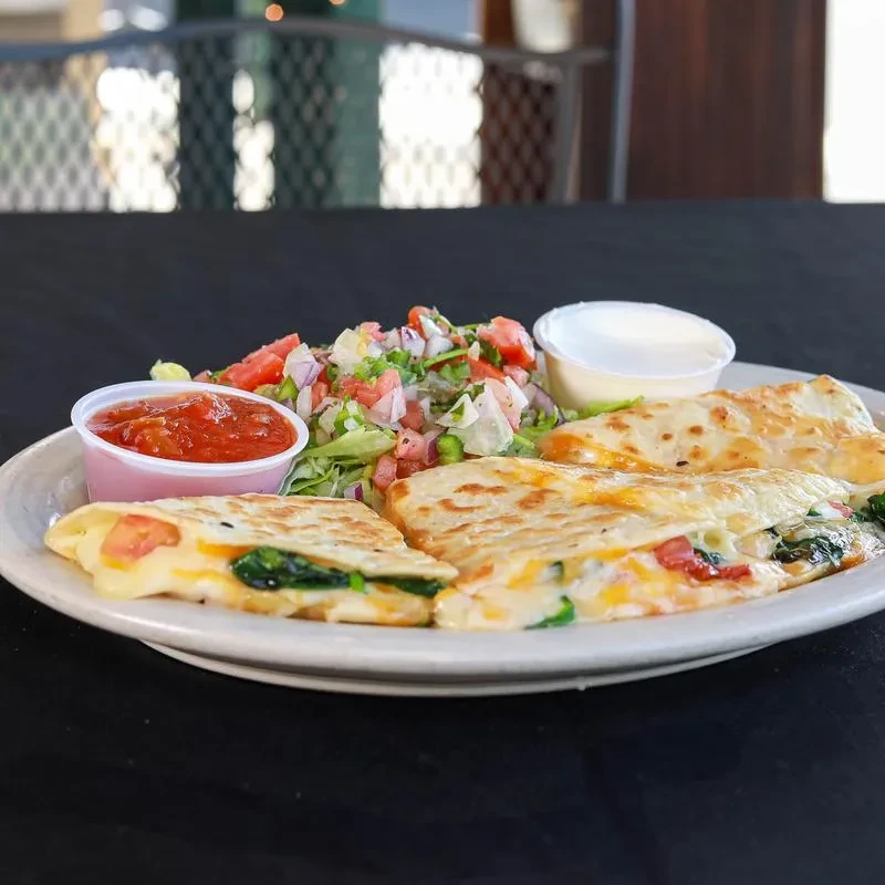 Golden quesadillas with side salad, red salsa, and sour cream.