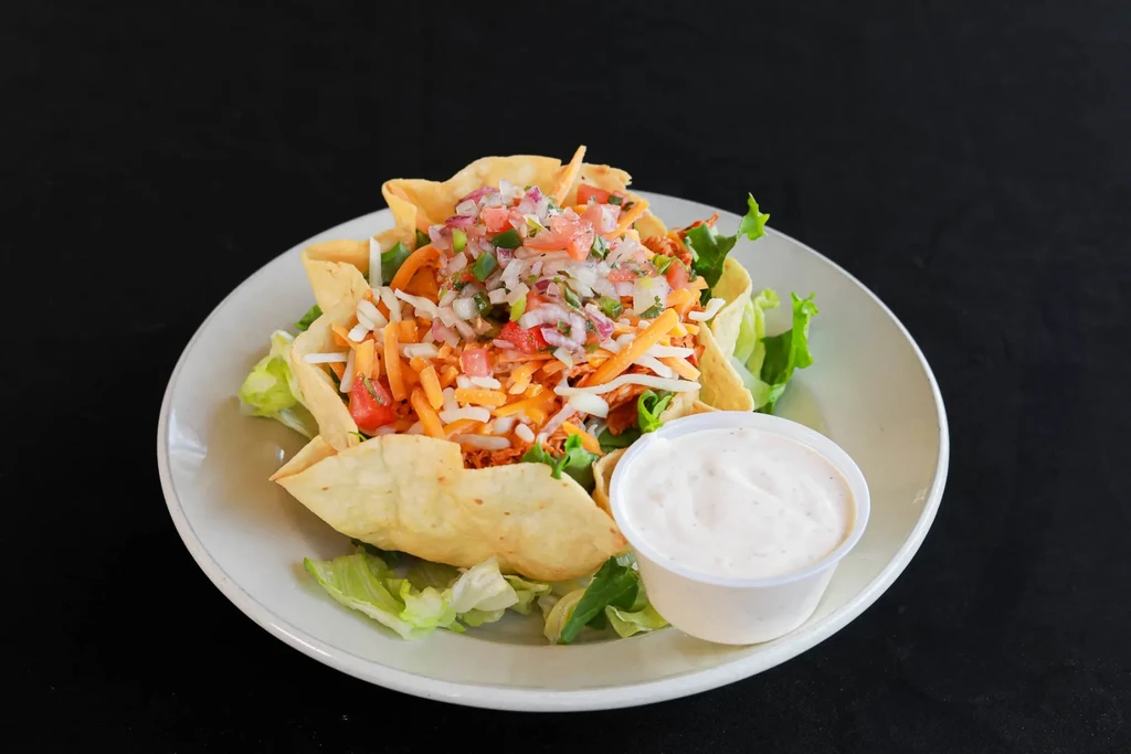 Crispy tortilla bowl taco salad with meat, cheese, pico, and dressing.