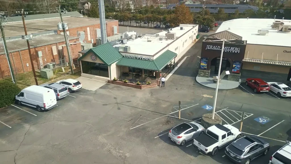High-angle shot: Eddie's Place (green roof), Jerald Melberg Gallery, large parking lot.