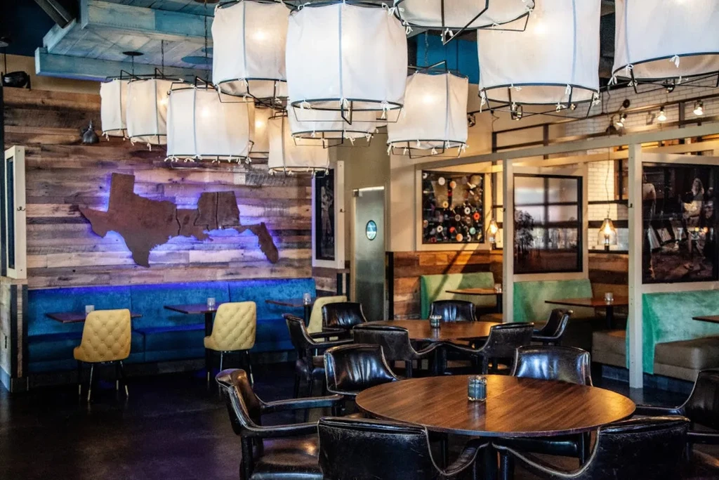 Modern-rustic restaurant interior with blue banquette and illuminated US states art.