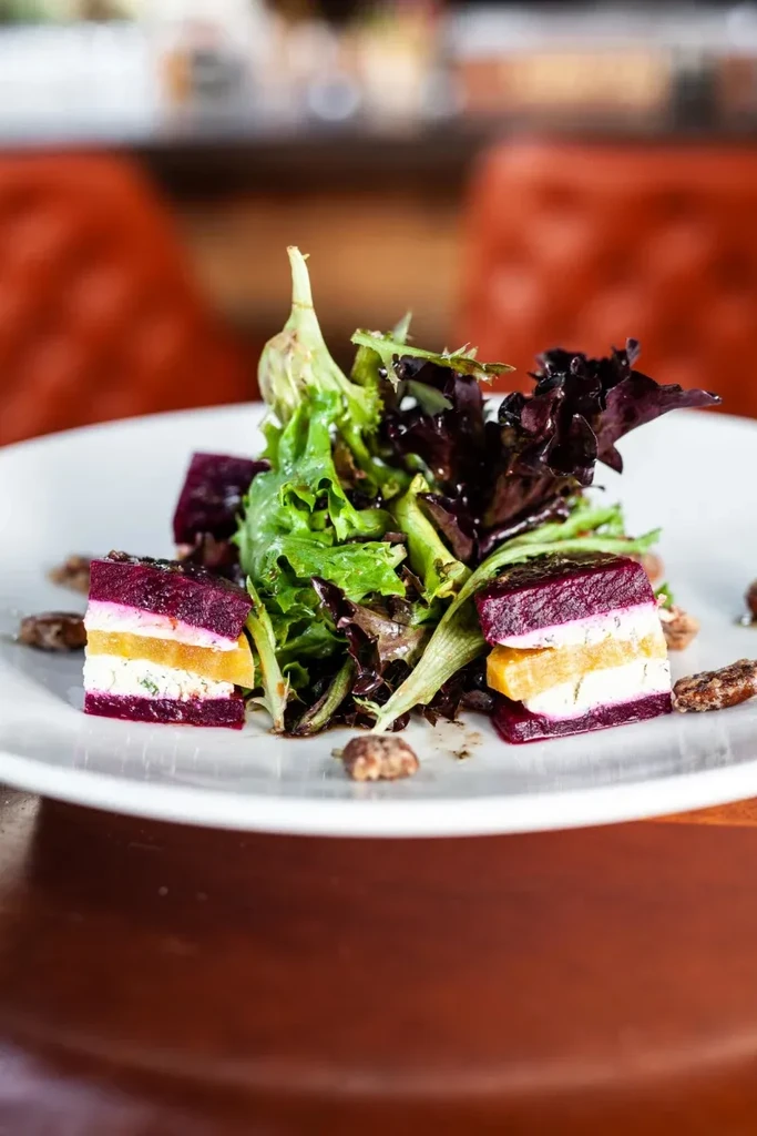 Salad with mixed greens, layered beet segments, and pecans.