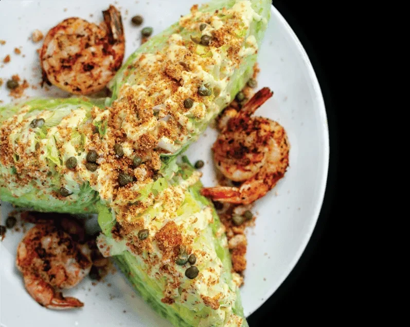 Grilled shrimp and wedge salad with dressing, breadcrumbs, and capers.
