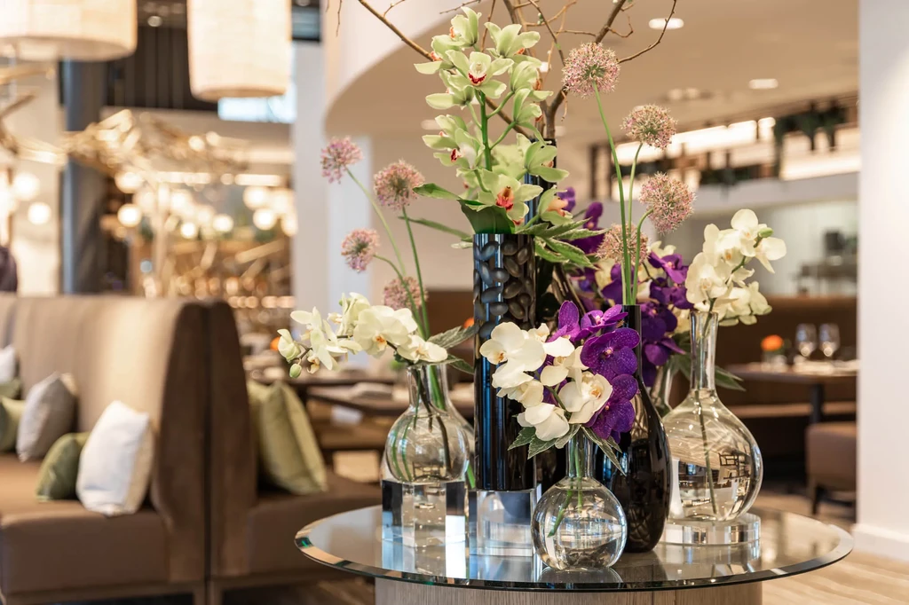 Vibrant orchid and allium floral arrangement on table in elegant restaurant.